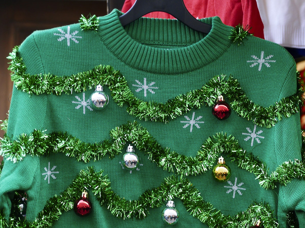 A green Christmas jumper with tinsel and baubles on it